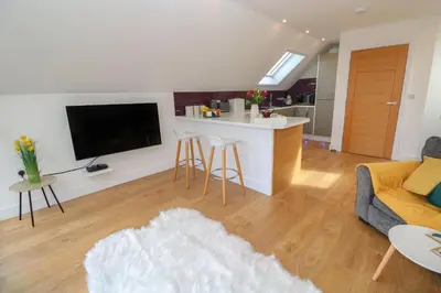 a living room with a couch and a kitchen at Cuckoo's Rest in Penryn