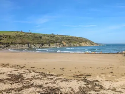 a beach with the ocean and a hill in the background at Carrick Cottage in Falmouth