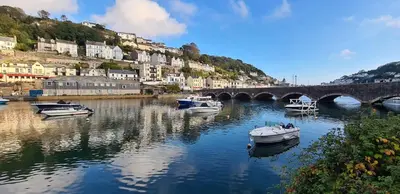 a group of boats in a river with a bridge at 1 Bake Cottage Serenity - Premium Coastal Retreat in Looe, Cornwall in Looe