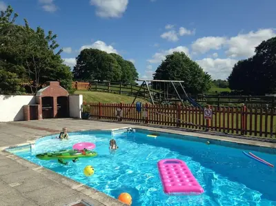 a swimming pool with two kids in a playground at Siblyback Cottage in Launceston