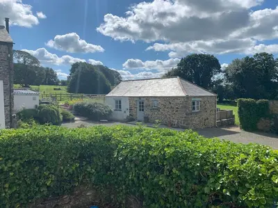a stone house in a yard with a hedge at Siblyback Cottage in Launceston