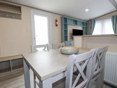 a kitchen and dining room with a wooden table and chairs at The Mermaid A04 in Par