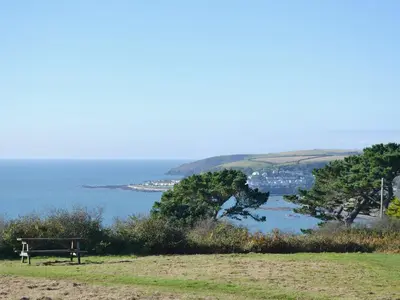 a bench sitting on top of a hill near the ocean at Linhay in Looe
