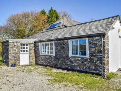 a stone cottage with a white door and windows at Bray View Cottage in Davidstow