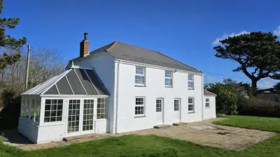 a white house with a gambrel roof at Meadow House in Porthscatho