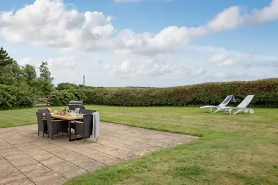 a patio with a table and chairs in a field at Meadow House in Porthscatho