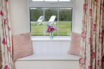 a window with a vase of flowers on a window sill at Meadow House in Porthscatho