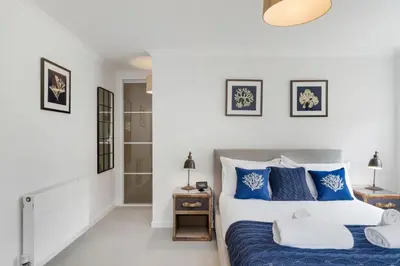 a bedroom with a bed with blue and white pillows at The Little Hawthorns in Polzeath