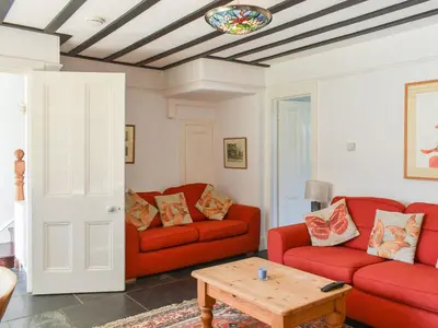 a living room with two red couches and a table at Nessa Cottage - Uk47087 in Davidstow