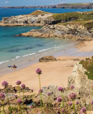 a beach with people in the water and a boat at Palms 1 Log Burner Private Courtyard Parking Central Newquay in Newquay