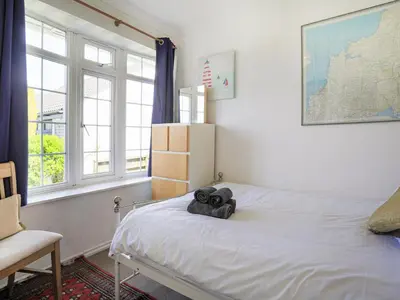 a bedroom with a white bed with a chair and windows at 31 Lower Elms in Saint Minver