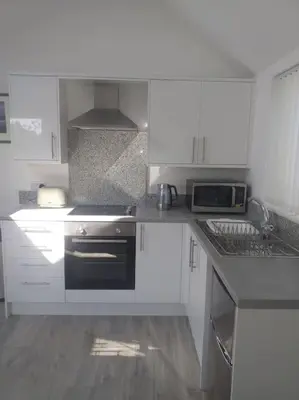 a kitchen with white cabinets and a black stove at Lanarth Chalet in Hayle Cornwall in Hayle
