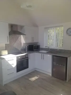 a kitchen with white cabinets and a stove top oven at Lanarth Chalet in Hayle Cornwall in Hayle
