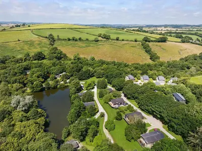 an aerial view of a farm with a lake at 10 Stonerush Valley in Looe