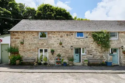 a stone house with two benches in front of it at River Cottage, Chypons Farm, Rural St Ives in Nancledra
