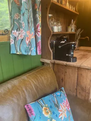 a brown leather couch in a room with a coffee shop at The Goose Nest luxury lakeside shepherd hut in Cardinham Woods, Cornwall in Cardinham
