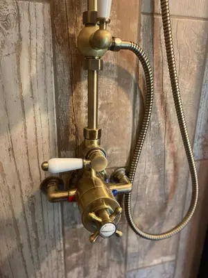 a brass shower faucet attached to a wall at The Goose Nest luxury lakeside shepherd hut in Cardinham Woods, Cornwall in Cardinham