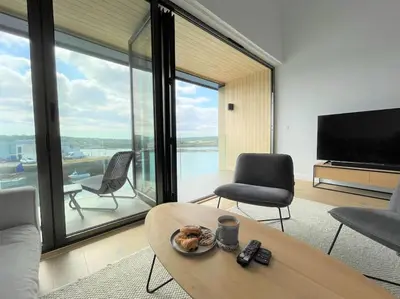 a living room with a table and chairs and a television at Luxury Waterfront 3 Bedroom/3 Bathroom Townhouse in Hayle