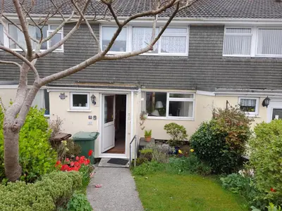 a house with a white door and a yard at Penny's Place in Carbis Bay