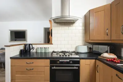 a kitchen with wooden cabinets and a stove top oven at Wheal Francis - Hot Tub - Accessible Bungalow - Free Wi-Fi - Parking in Helston