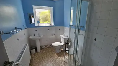 a blue bathroom with a toilet and a sink at Chywartha in Porthscatho
