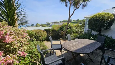 a wooden table and chairs with a table and flowers at Chywartha in Porthscatho