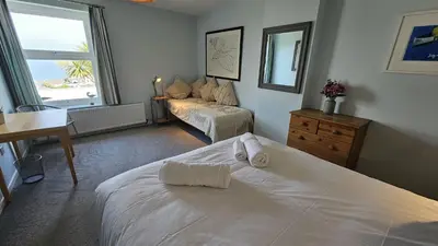 a bedroom with a bed and a desk and a window at Chywartha in Porthscatho