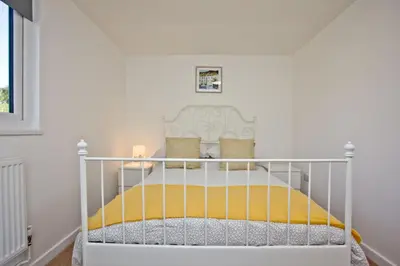 a white crib in a white room with a bed at Wheal Rose - Hot Tub - Parking - Free WiFi - On-Site Activities in Helston