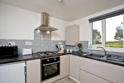 a kitchen with white cabinets and a stove top oven at Wheal Amelia - Free WiFi - Parking - Pet Friendly - On-site Activities in Helston