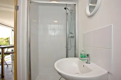 a white bathroom with a sink and a shower at Wheal Amelia - Free WiFi - Parking - Pet Friendly - On-site Activities in Helston
