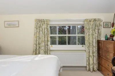 a bedroom with a bed and a window with curtains at Deugh an Chy in Carleen