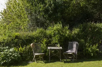 two chairs and a table in a garden at Deugh an Chy in Carleen