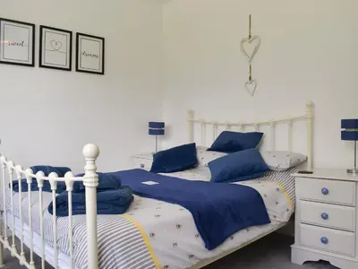 a bedroom with two beds with blue and white sheets at Trelawney Bungalow in Callington