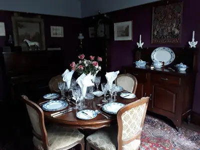 a dining room table with plates and flowers on it at Halcyon Days in Kenwyn