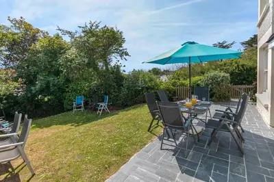 a patio with a table and chairs and an umbrella at 5 Bed in Trebetherick oc-b29371 in Polzeath