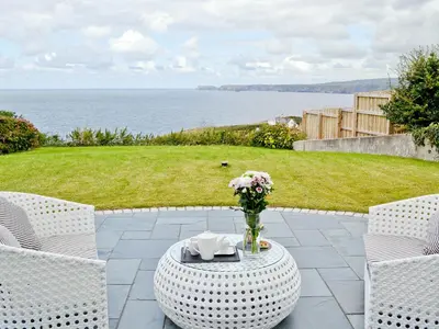 a table with a vase of flowers on a patio at Sea Vista in Port Isaac