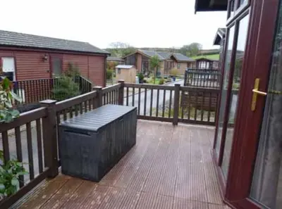 a wooden deck with a bench on a porch at Rosewater Park Lodge in Bodmin