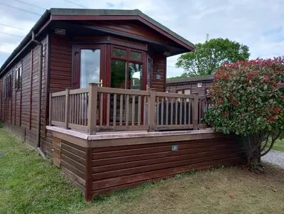 a wooden cabin with a porch and a deck at Rosewater Park Lodge in Bodmin