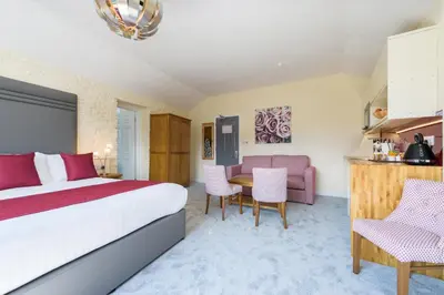 a hotel room with a bed and a table and chairs at Best Western Fowey Valley in Lostwithiel