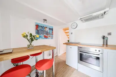 a kitchen with a counter and red stools in it at Fowey, Cute Cottage in Fowey