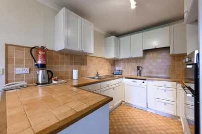 a kitchen with white cabinets and white appliances at Golf View 80 in Camborne