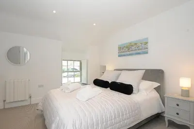 a bedroom with a large white bed with pillows at Cob Cottage in Wadebridge