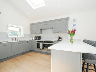 a kitchen with gray cabinets and a white counter top at Cob Cottage in Wadebridge