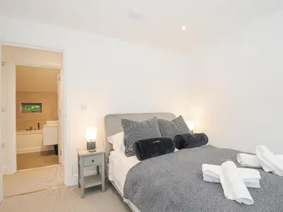 a white bedroom with a bed with black pillows at Cob Cottage in Wadebridge