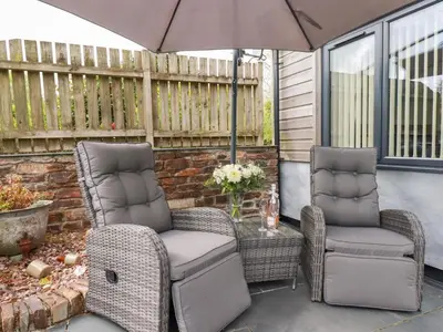 two chairs and an umbrella on a patio at The Stables in Saint Columb Major