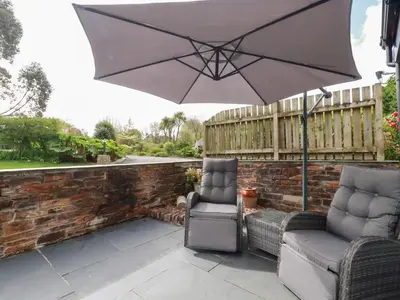 two chairs and an umbrella on a patio at The Stables in Saint Columb Major