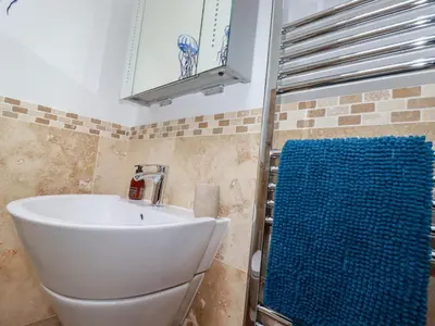 a bathroom with a white sink and a toilet at The Stables in Saint Columb Major