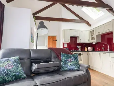 a living room with a couch and a kitchen at The Stables in Saint Columb Major