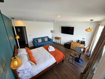 a bedroom with a large bed and a blue couch at Premier 2 - Stunning Suite with Breathtaking Seaside Views in St Ives