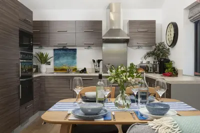 a kitchen with a wooden table with plates and wine glasses at Landing View Fowey Penthouse in Fowey